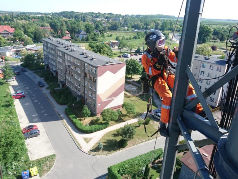 Montaż instalacji przemysłowych, spawanie na wysokościach, pracownik na wysokości w masce spawalniczej, Climbnet